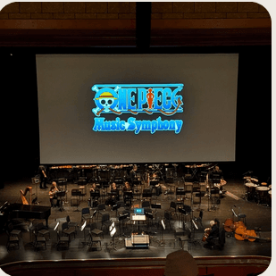 A live orchestra stage with a One Piece screen.